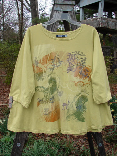 Barclay Three Quarter Sleeved A Lined Tee Garden Friends Mottled Plantain Size 0, featuring a patterned yellow fabric, sweet curly edgings, and a rounded rolled neckline, showcased outdoors.
