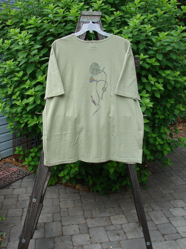 2001 NWT Short Sleeved Tee Junk Drawer Kelp Size 2 displayed on a hanger, showcasing its drop shoulders, wide short sleeves, and detailed junk drawer theme paint.