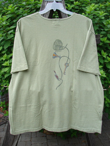 2001 NWT Short Sleeved Tee Junk Drawer Kelp Size 2 displayed on a hanger, featuring a slightly thinner neckline, drop shoulders, wide short sleeves, and intricate junk drawer theme paint with the Blue Fish logo on the back.