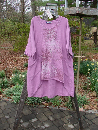 Barclay NWT Linen Poset Tunic Dress Clover Field Orchid Size 0 displayed on a wooden rack, showcasing its flowy figure-eight shape and exterior drop front pockets.