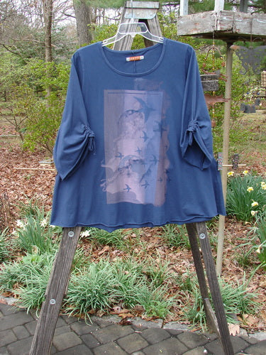 Barclay Draw Sleeve Cafe Tunic Moon Gull Denim Size 1 displayed on a wooden rack, showcasing its rounded neckline, swinging A-line shape, long cozy sleeves, and moon gull theme paint.