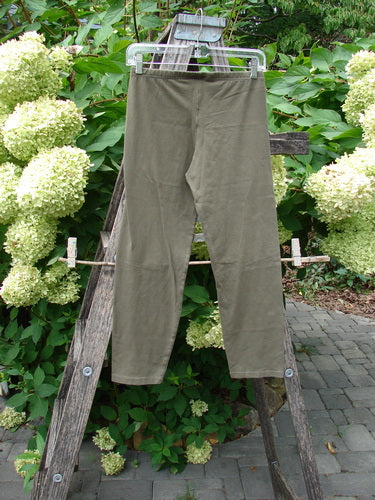 Barclay NWT Cotton Lycra Crop Legging Unpainted Brown Earth Size 0 hangs on a wooden rack outdoors, showcasing its lightweight fabric and elastic waistband, emphasizing casual elegance from Bluefishfinder.com.