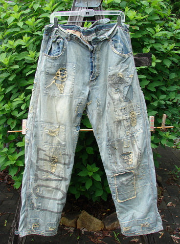 Magnolia Pearl NWT Guadalupe Love Ranchero Miner Jean in Washed Indigo, featuring distressed edges, continuous patching, rear embroidery, adjustable buckle tab, and dual rear pockets, showcasing a generous leg width and button fly.