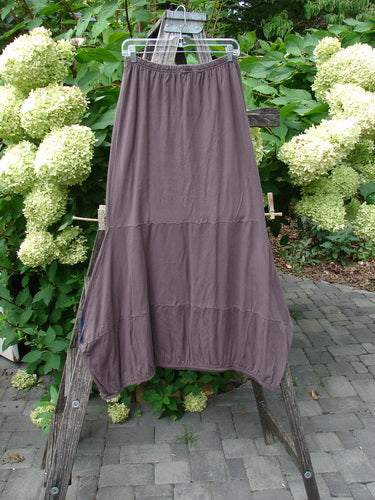 Barclay NWT Sprig Skirt Grid Garden Brown Sparrow Size 0, featuring a tiered, elastic-waist design, hangs on a wooden ladder amidst lush greenery and white flowers, highlighting its unique garden-themed paint.