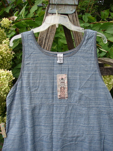 Barclay NWT Light Weight Chambray Shift Stripe Denim Light Size 0, featuring a scoop neckline and varying hem, hangs on a garden trellis, showcasing its unpainted, lightweight linen texture.