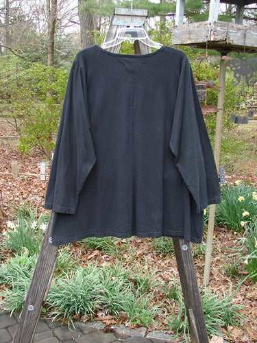 Barclay NWT Long Sleeve Studio Tee in Mixed Metallic Mosaic Black, displayed on a wooden rack, showcases its A-line shape and rolled neckline.