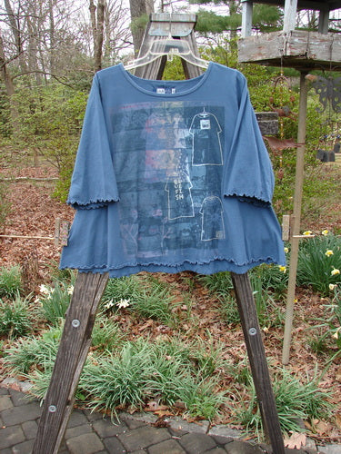 Barclay Three Quarter Sleeved Crop A Lined Tee Play Dress Up Navy Size 0 displayed on a wooden easel, showcasing its unique A-line shape, rounded neckline, and curly edgings against a natural outdoor backdrop.