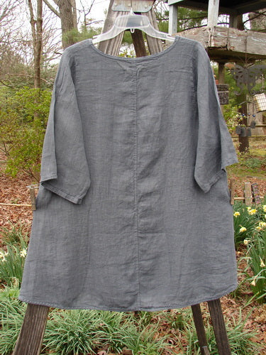 Barclay NWT Linen Lucida Top Fern Fare Steel Blue Diatom Size 0 draped on a wooden pole, showcasing a flowy A-line shape with three-quarter sleeves and a rounded neckline.