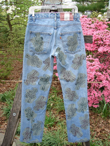 1995 Levi Strauss & Co Denim Blue Jean Leaves Stone Wash Size 1, featuring a dark oak-leaf pattern, hangs outdoors with azaleas in the background, showcasing vintage charm and exquisite detailing.