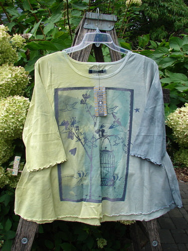 Barclay NWT Three Quarter Sleeved Cafe Tee Free Bird Mottled Violet Citron Size 0, featuring bird-themed graphic print, wavy trim, and clear hanger display against ladder with floral backdrop.