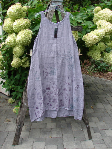 Barclay NWT Linen Sundress Garden Folly Amethyst Size 0, featuring a sleeveless design with a rounded neckline, empire waist, floral motif, and varying hemline, displayed on a wooden A-frame.