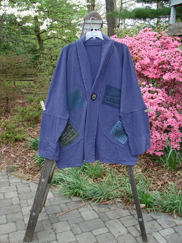 1995 Reprocessed Deco Jacket Jeweled Flower Button Royal Orchid OSFA displayed on a swing, featuring patchwork designs, long arm lengths, deep V neckline, and oversized painted pockets.