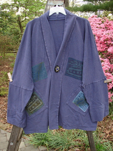 1995 Reprocessed Deco Jacket Jeweled Flower Button Royal Orchid OSFA displayed on a wooden pole, featuring patchwork designs, drop dolman shoulders, and oversized painted pockets.