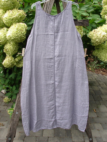 Barclay NWT Linen Sundress in Garden Folly Amethyst Size 0, featuring a loose-cut design with a rounded neckline and varying hemline, displayed outdoors against blooming hydrangeas.