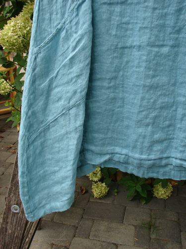 Barclay NWT Linen Zen Pocket Tunic Dress Unpainted Turquoise Size 0, draped over a weathered wooden bench, features three-quarter sleeves, dual pockets, and an A-line shape with a unique hem.