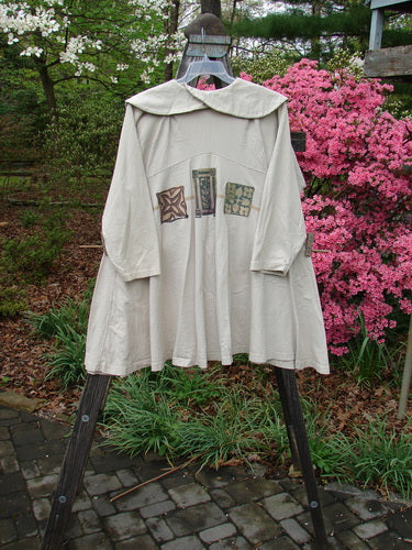 1994 Wanderer's Jacket Mindful Mosaic Mist Altered Size 1 on a rack, showcasing wide shawl collar, downward yoke, sectional side inserts, and unique shoulder folds.