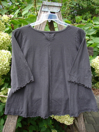 Barclay NWT Three Quarter Sleeved Crop Cafe Tee Many Fish Black Sand Size 0 features flared sleeves, a ruffled hem, and a rolled neckline, displayed on a wooden ladder against a garden backdrop.