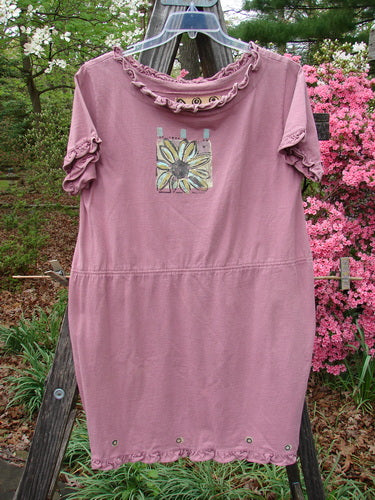 1991 Milkmaid Dress Daisy Dusty Pink OSFA: A pink dress with a daisy pattern, featuring a drop waistband and curly neck hem, displayed on a clothes rack.