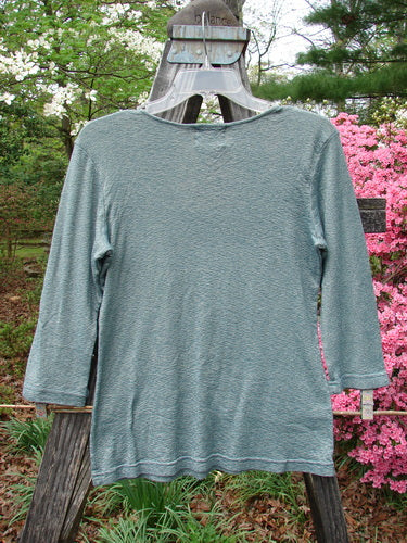 2000 Litmus Squareneck Top Unpainted Puddle Size 1 displayed on a hanger, showcasing its wide, slightly squared neckline and neatly stitched accents, highlighting its flattering drape and slightly flared hip measurement.