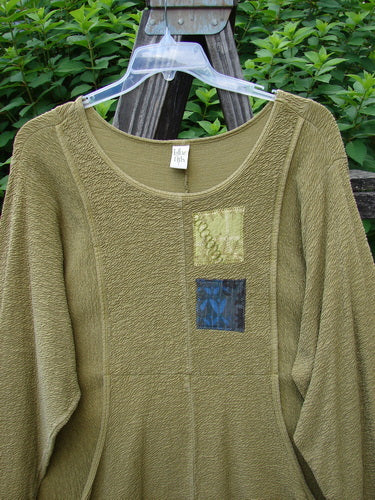 Barclay Patched Crepe Perennial Tunic Top Woods Olive Size 2: Green sweater with patchwork designs, featuring two front pockets, curved empire waist, banded sleeves, and a rounded neckline.