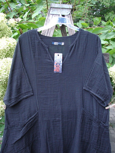 Barclay NWT Gauze Keyhole Bliss Pocket Dress Unpainted Black Size 0, displayed outdoors on a hanger, features a V-neck, elbow-length sleeves, front pockets, and a unique keyhole neckline in soft double cotton gauze.