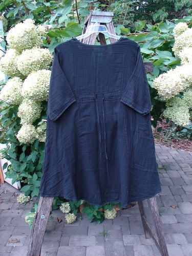 Barclay NWT Gauze Keyhole Bliss Pocket Dress Unpainted Black Size 0, hanging on a wooden ladder, features a round neckline, elbow-length sleeves, waist tie, and triangular drop pockets in soft double cotton gauze.