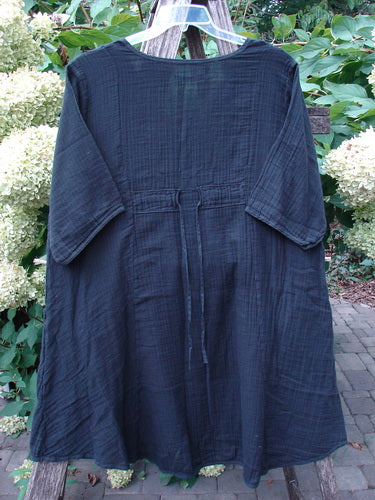 Barclay NWT Gauze Keyhole Bliss Pocket Dress Unpainted Black Size 0, features a keyhole neckline, triangular drop pockets, three-quarter sleeves, and drawcord back, displayed on a hanger with foliage backdrop.