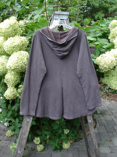 Barclay NWT Fleece Sweet Pocket Hoodie Contour Daisy Brown Sparrow Size 0 displayed on a wooden ladder, showcasing its cordless hood, A-line shape, and exterior drop roo pocket amidst a garden backdrop.