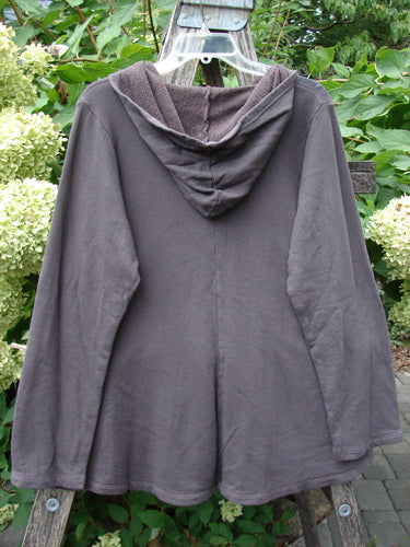 Barclay NWT Fleece Sweet Pocket Hoodie Contour Daisy Brown Sparrow Size 0, featuring a flared hem and cordless hood, hangs outdoors on a clear plastic hanger, highlighting its unique cape-style design.