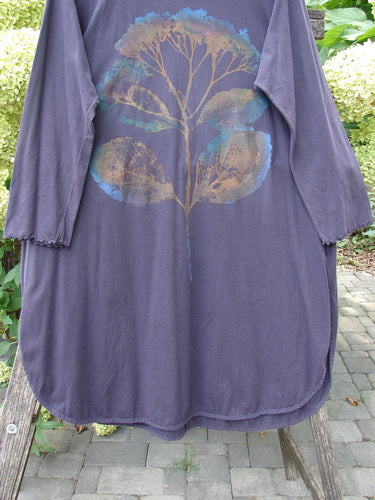 Barclay NWT Natalia Tunic in Dried Floral Metallics Plum River Size 1, featuring a stylized tree motif on the back, rounded neckline, and sweet lettuce-edged sleeves, draped over an outdoor wooden bench.