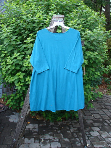 Barclay NWT High Low Top Unpainted Pacific Aqua Size 2 displayed on a swinger, showcasing its A-line shape, rounded banded bottom, and three-quarter sleeves.