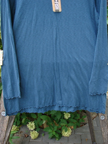 Barclay NWT Modal Slub Long Sleeved Simple Tee Unpainted Morocco Size 0, displayed on a wooden ladder amid greenery, features ruffled edges, an A-line shape, and a rounded neckline.