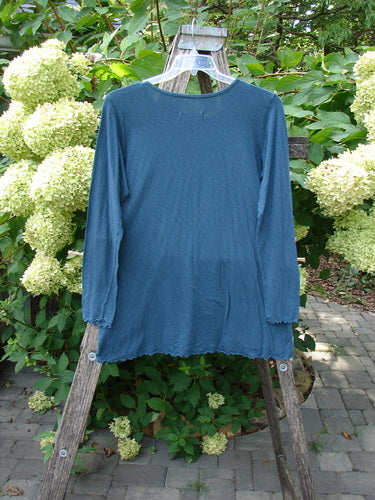Barclay NWT Modal Slub Long Sleeved Simple Tee Unpainted Morocco Size 0 displayed on a rustic wooden ladder, showcasing its A-line shape, raw edges, and rounded neckline amidst lush greenery.