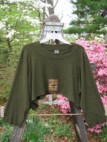 2000 Patched Rayon Lycra Rib Overtop Green Oak Heather Size 1 displayed on an outdoor swing, showcasing its unique texture, upward scooping hemline, and Celtic-themed painted patches.