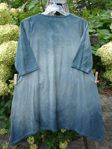 Barclay NWT Wander Tunic Tee Moon Fern Mottled Grey Green Size 0 on hanger, showcasing its loose cut, short sleeves, and slight A-line flair, set against lush hydrangea blooms and garden foliage.