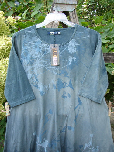 Barclay NWT Wander Tunic Tee Shadow Blossom Mottled Grey Green Size 0 displayed on a hanger outdoors, showcasing its longer tunic length, slight A-line flair, and rounded neckline against leafy foliage.