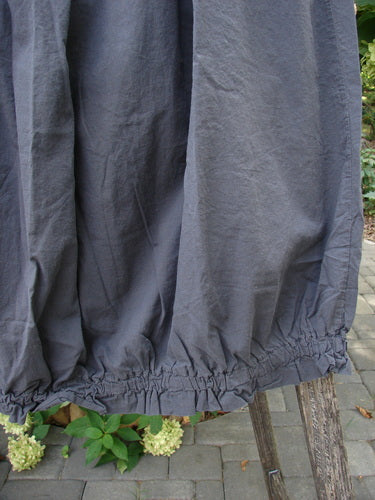 Barclay NWT Batiste Airy Lawn Skirt Unpainted Black Sand Size 0, showcasing a loose-fitting slate-gray garment with a gathered, elasticized hem, hanging outdoors against a natural backdrop.