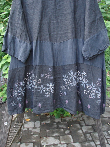 Barclay Linen Wonderland Sectional Banded Cardigan Lucky 4 Black Size 2 featuring a floral design, scooped neckline, belled lower sleeves, and thick pearly buttons, displayed on an outdoor stone walkway.