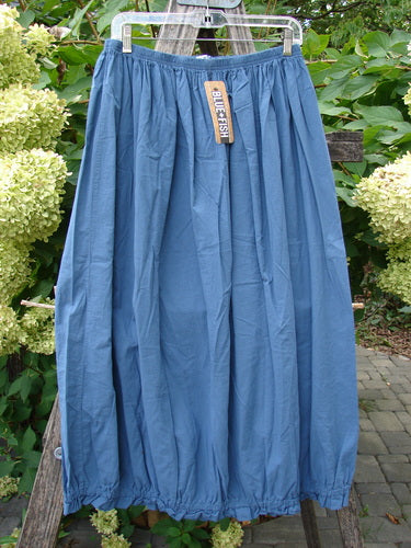 Barclay NWT Batiste Airy Lawn Skirt Unpainted Echo Blue Size 0, featuring a full elastic waistband and bubble hem, elegantly displayed with a Blue Fish tag against lush foliage.