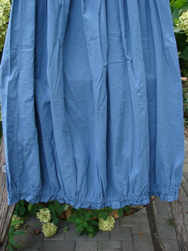 Barclay NWT Batiste Airy Lawn Skirt Unpainted Echo Blue Size 0, displayed outdoors, showcases a loose, ankle-length drape over a wooden support, emphasizing its lightweight cotton batiste and full elastic waistline.