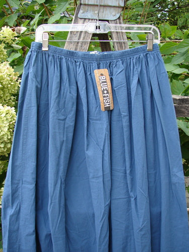 Barclay NWT Batiste Airy Lawn Skirt Unpainted Echo Blue Size 0 displayed outdoors on a metal hanger against a wooden structure, showcasing its gathered hem and full elastic waist.