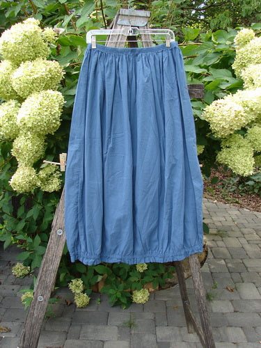 Barclay NWT Batiste Airy Lawn Skirt Unpainted Echo Blue Size 0 displayed on a clear hanger over a wooden ladder, highlighting its full elastic waist and barrel shape in a garden setting.