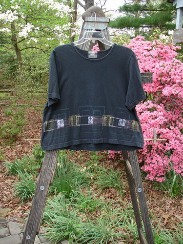 2000 Short Sleeved Crop Tee Transition Black Size 1 displayed on a wooden stand, highlighting its wide crop box shape and flat finished neckline, part of the mid-weight organic cotton Spring Collection.