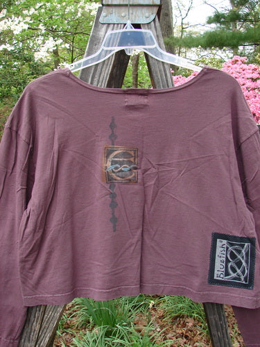 2000 Kell's Top Celtic E Loam Size 1 displayed on a hanger, featuring a long sleeve, boxier shape, and signature Blue Fish patch with a bright Celtic letter E design.