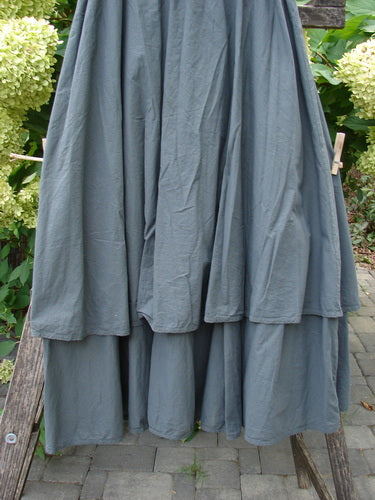 Barclay NWT Batiste Fold Over Stardust Tier Skirt in Atlas Grey, displayed draped over a wooden ladder outdoors. This multi-layered skirt features a forgiving waistline and two-tiered A-line design.
