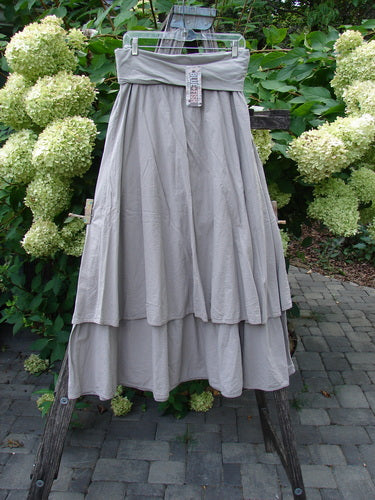 Barclay NWT Batiste Fold Over Stardust Tier Skirt Moon Rock Sand Size 0 displayed on a clear hanger, tiered design, showcases a layered, lightweight cotton batiste with generous, flowing dimensions.