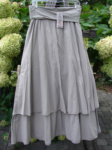 Barclay NWT Batiste Fold Over Stardust Tier Skirt Moon Rock Sand Size 0, displayed outdoors, features a two-tiered, light gray cotton design with a folded waistband, showcasing its flowing, generous A-line silhouette.