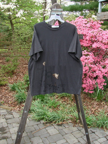 1998 Botanicals Short Sleeved Tee Macro Raven Size 2 displayed on a hanger, featuring a flower design, longer boxy shape, and softly ribbed neckline, highlighting its vintage charm from Bluefishfinder.com.