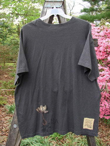 1998 Botanicals Short Sleeved Tee Macro Raven Size 2 displayed on a clothes rack, showcasing a longer boxy shape with a softly ribbed neckline and unique macro-themed floral design.