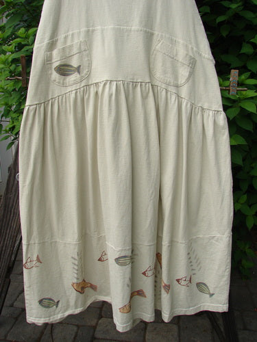 1999 NWT Tadpole Jumper Single Stripe Pike Natural OSFA: A white skirt with fish embroidery, featuring adjustable shoulder straps, sweeping hemline, criss-cross back, empire waistline, and two round-bottomed pockets.